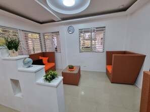 A modern living room with a sofa, a chair, a small table with a plant, and a globe on a shelf. - CMJ Private Resort  (Indang)
