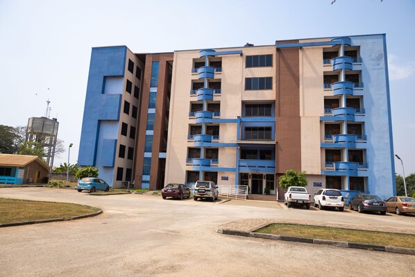 A multi-story building with a parking lot in front.