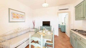 Un espacio habitable compacto con comedor, kitchenette y sofá.