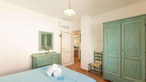 Un dormitorio con cama, cómoda, silla y armario.