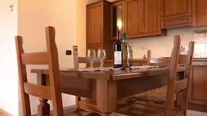 Ein Holztisch mit vier Stühlen, einer Weinflasche und drei Weingläsern auf einer Tischmatte.