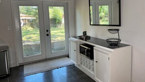 A kitchen with a white cabinet, a black countertop, and a double door leading to a backyard.