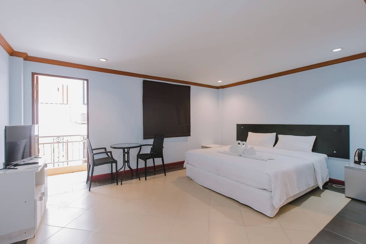 A hotel room with a bed, a desk with a computer, a chair, and a TV.