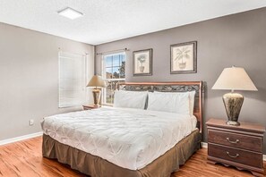 Une chambre à coucher avec un lit, des tables de chevet et une fenêtre avec des stores.