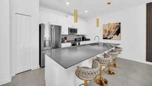 A modern kitchen with white cabinets, stainless steel appliances, and a central island with bar stools.