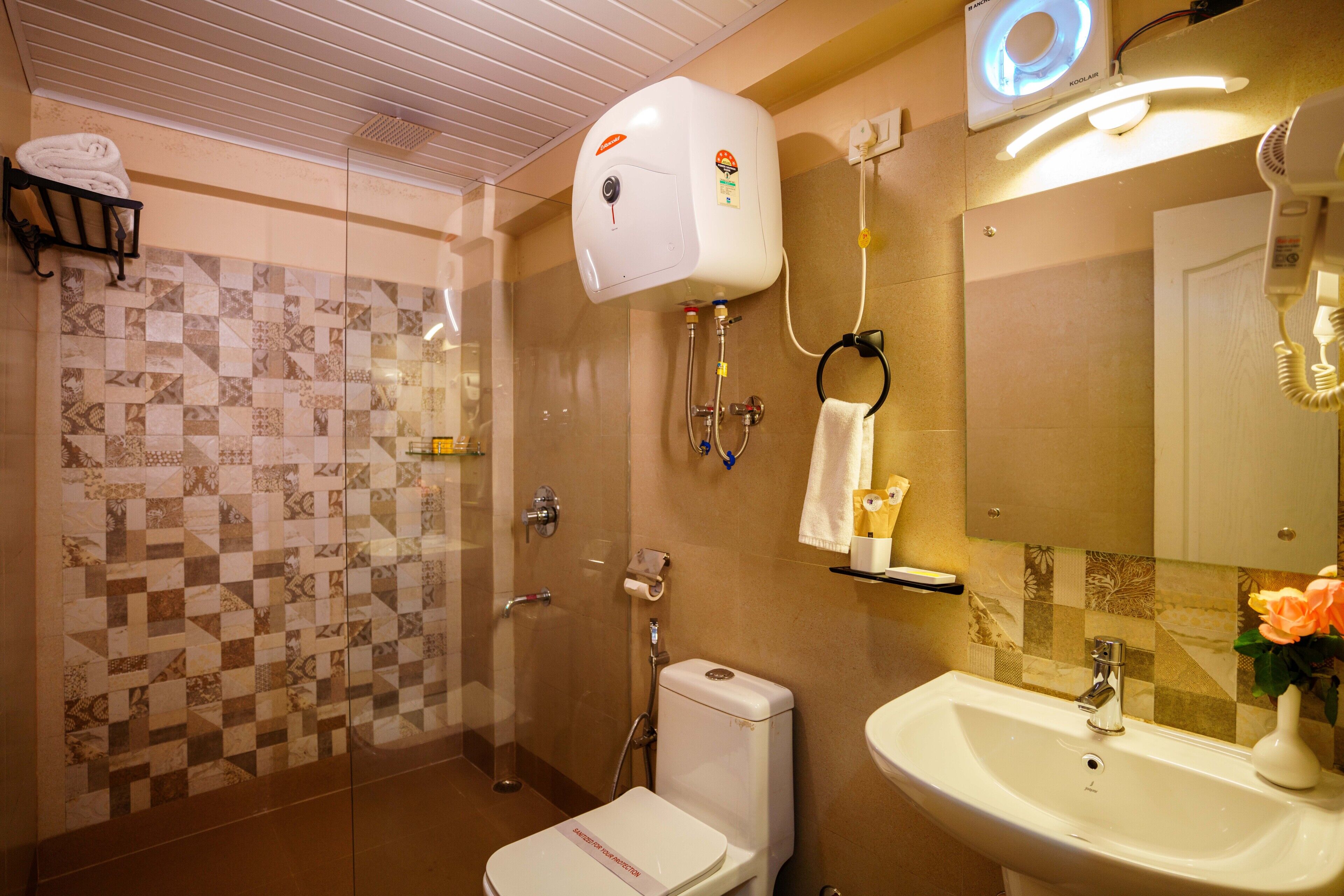 A bathroom with a shower, toilet, sink, and a mirror.