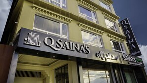 A multi-story building with a sign for 'QSAINA' and 'Mapham'.
