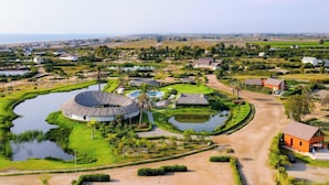 Un complexe hôtelier doté d’éléments aquatiques de forme circulaire, d’un bâtiment central et d’une végétation luxuriante tout autour.