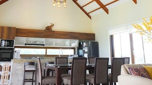 Une cuisine spacieuse, dotée d’appareils électroménagers modernes, et un coin repas avec des chaises et une table en bois.
