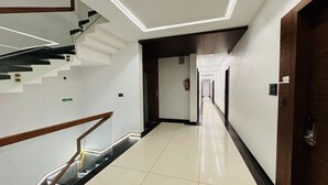 A hotel hallway with a staircase, a fire extinguisher, and a door with a number sign. - Hotel Rajdev INN  (Ujjain)
