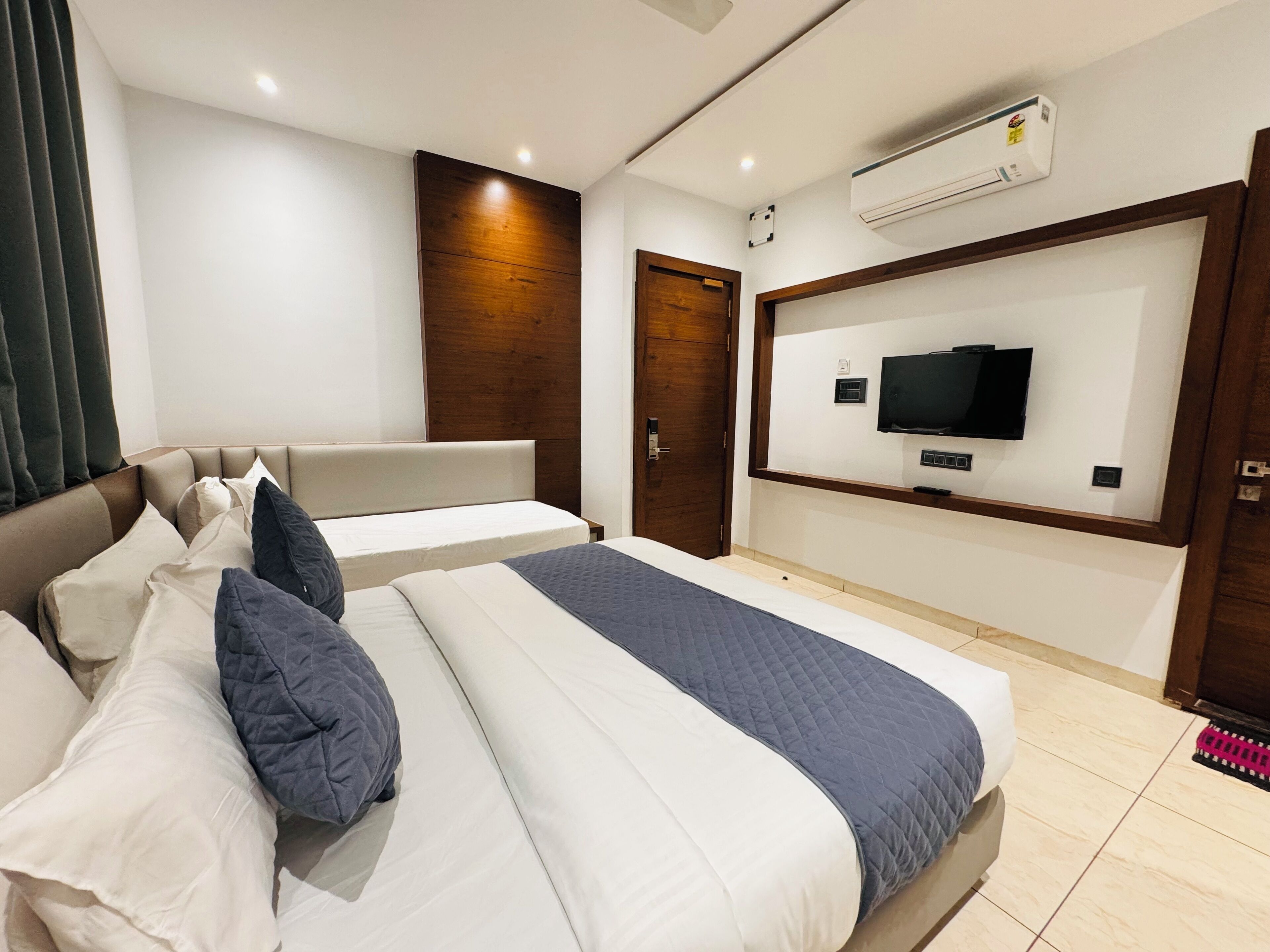 A modern hotel room with a large bed, a TV mounted on the wall, and a wooden door.
