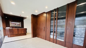 A reception area with a wooden reception desk, a framed picture on the wall, and a large sliding door with a metal mesh design. - Hotel Rajdev INN  (Ujjain)