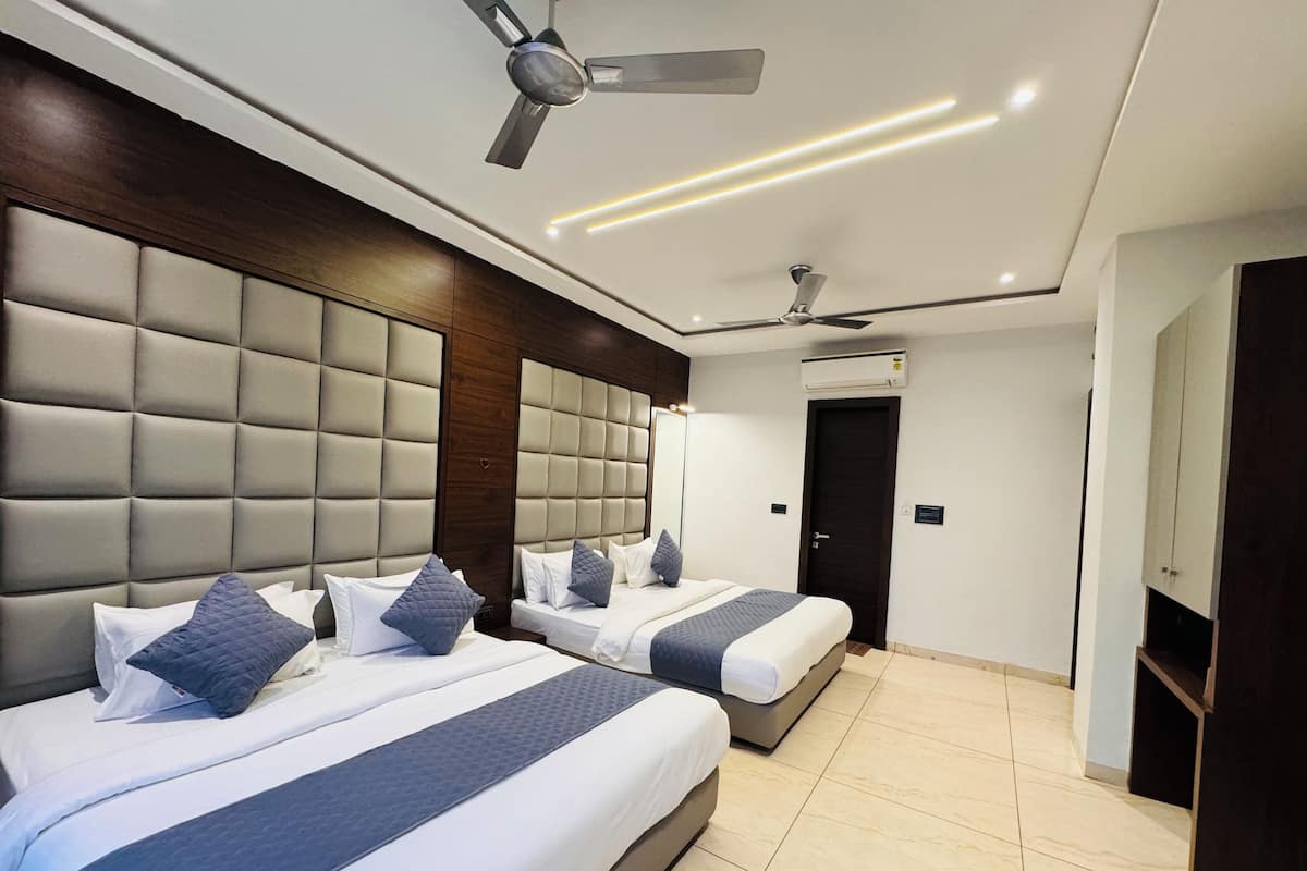 A hotel room with two beds, a ceiling fan, recessed lighting, and a wardrobe.