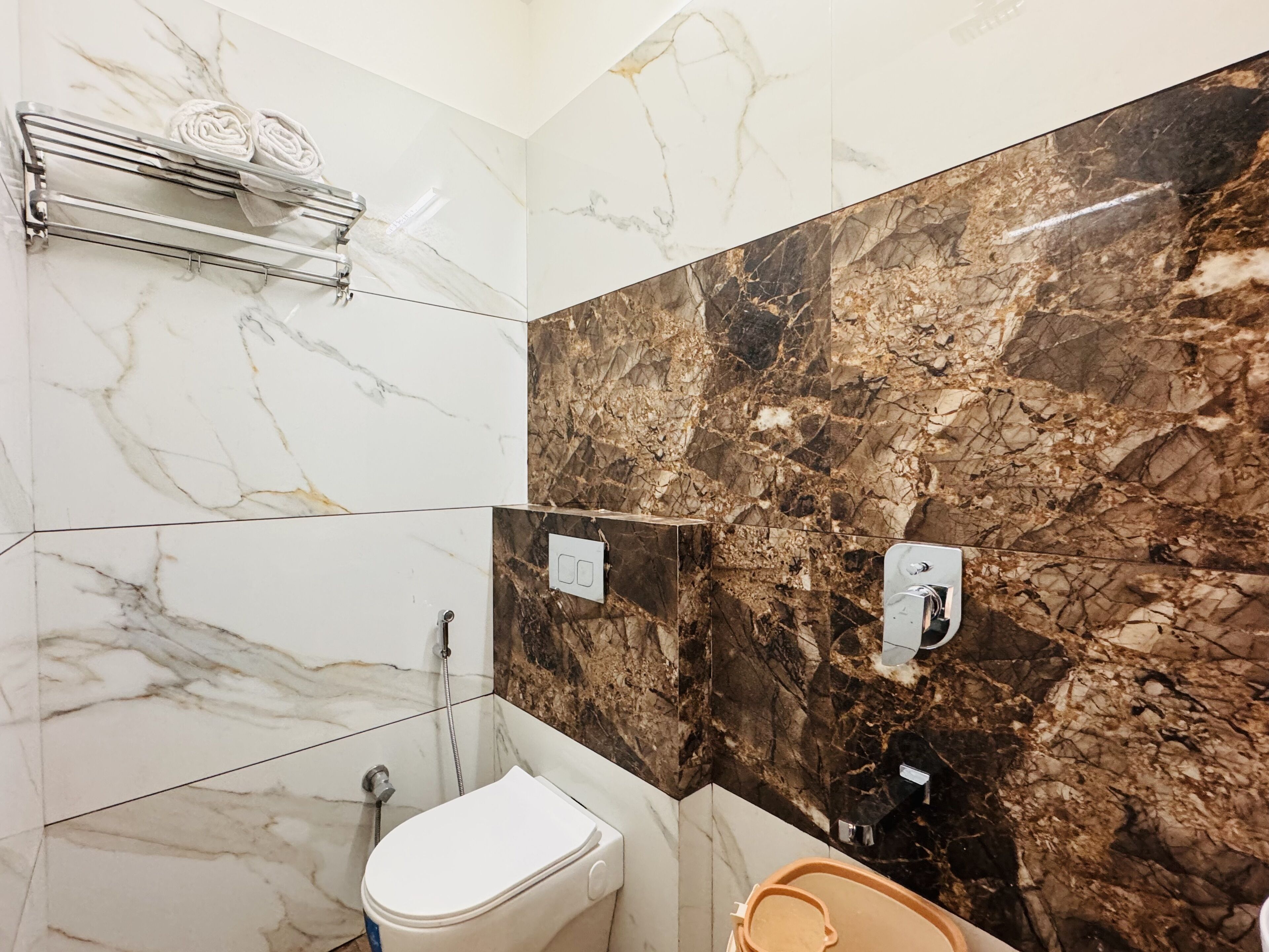 A bathroom with a toilet, a shower, and a towel rack.