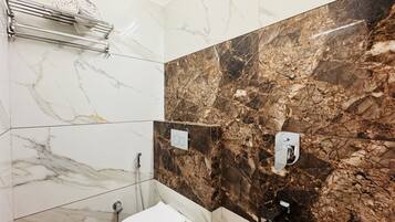 A bathroom with a toilet, a shower, and a towel rack.