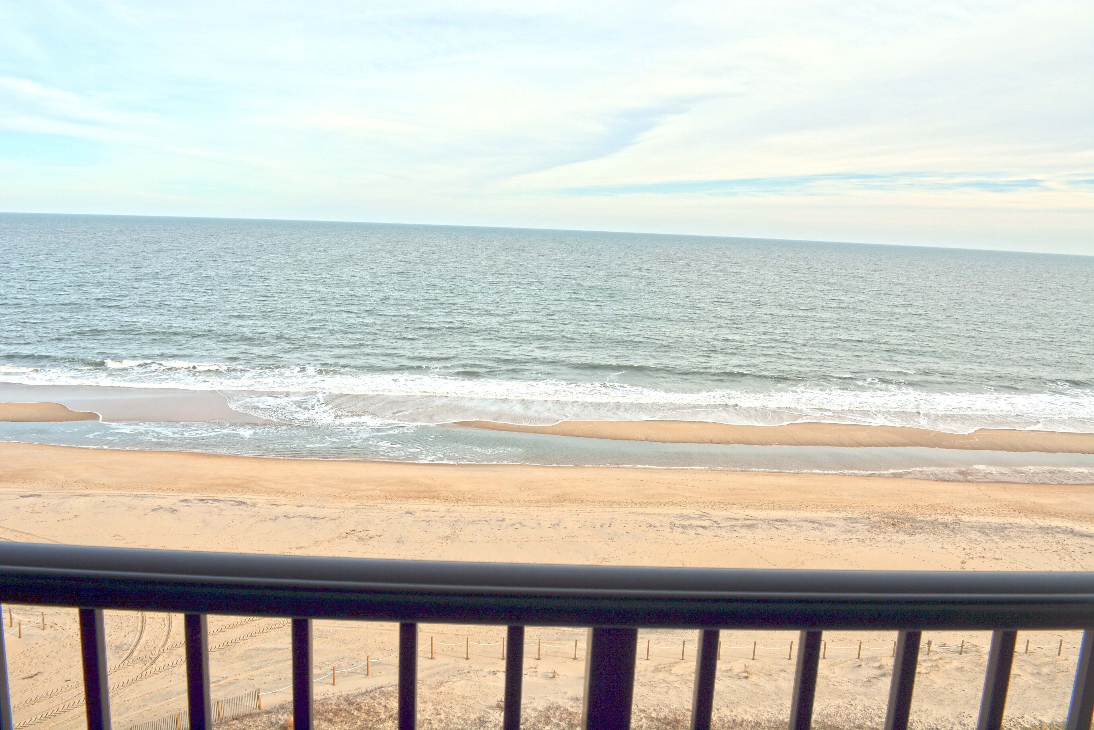 A beach view with a railing in the foreground.
