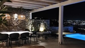 An outdoor patio with stone walls, a dining area, and a pool. - Mykonian Luxury Villa Azure w View Pool (Mykonos)
