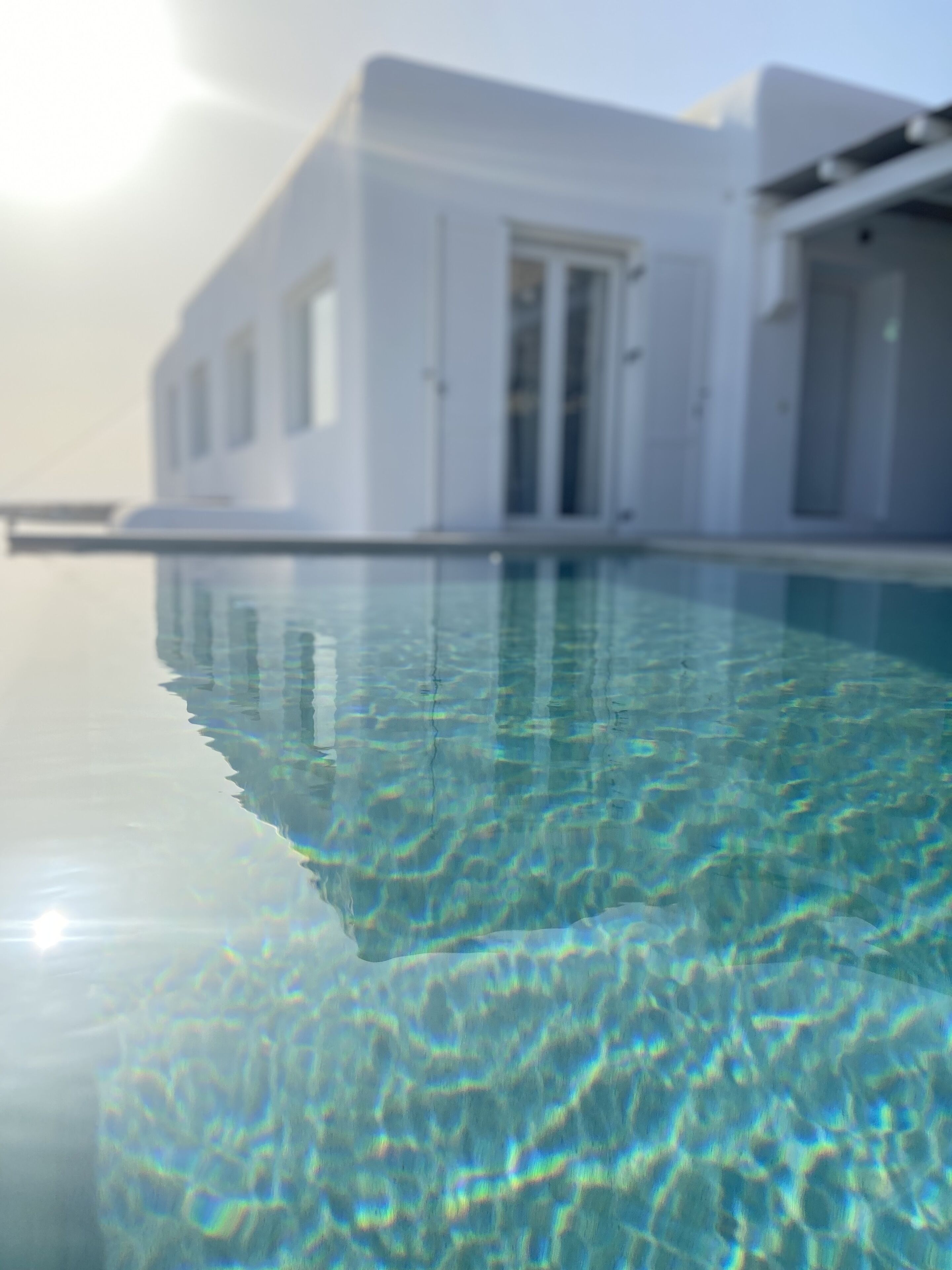 A clear swimming pool with a modern white building in the background.