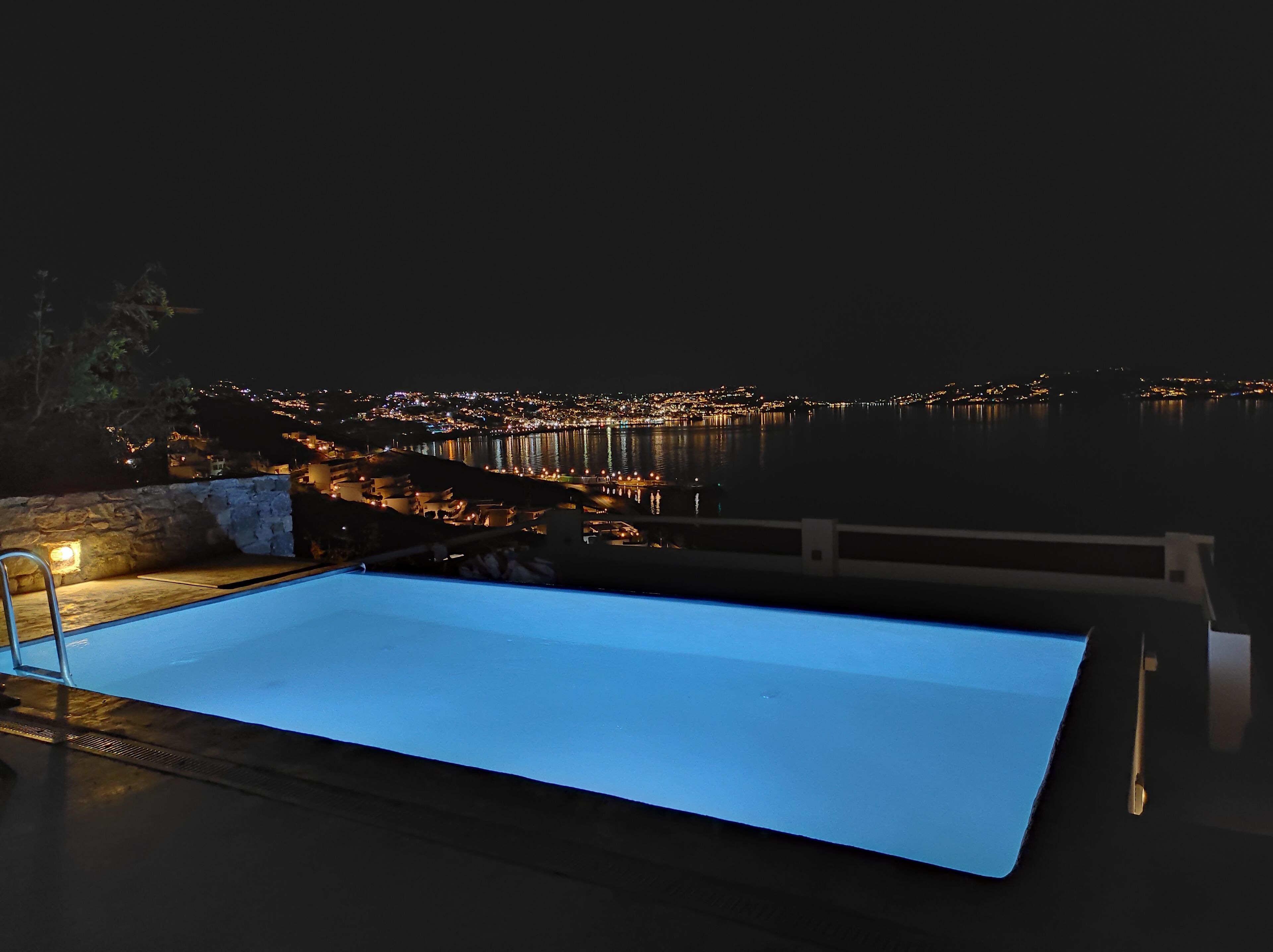 A swimming pool with a view of a cityscape at night.