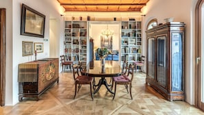 A dining area with a round table, chairs, bookshelves, a chandelier, and a large cabinet. - Trastevere Outstanding  4 BR Terraced Apartment (Roma)