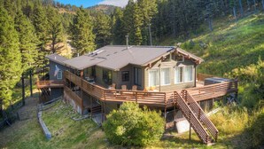 Une cabane dotée d’une terrasse, d’un escalier et offrant une vue sur la forêt environnante.