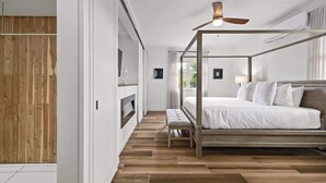 Un dormitorio moderno con cama con dosel, suelo de madera y ventilador de techo.