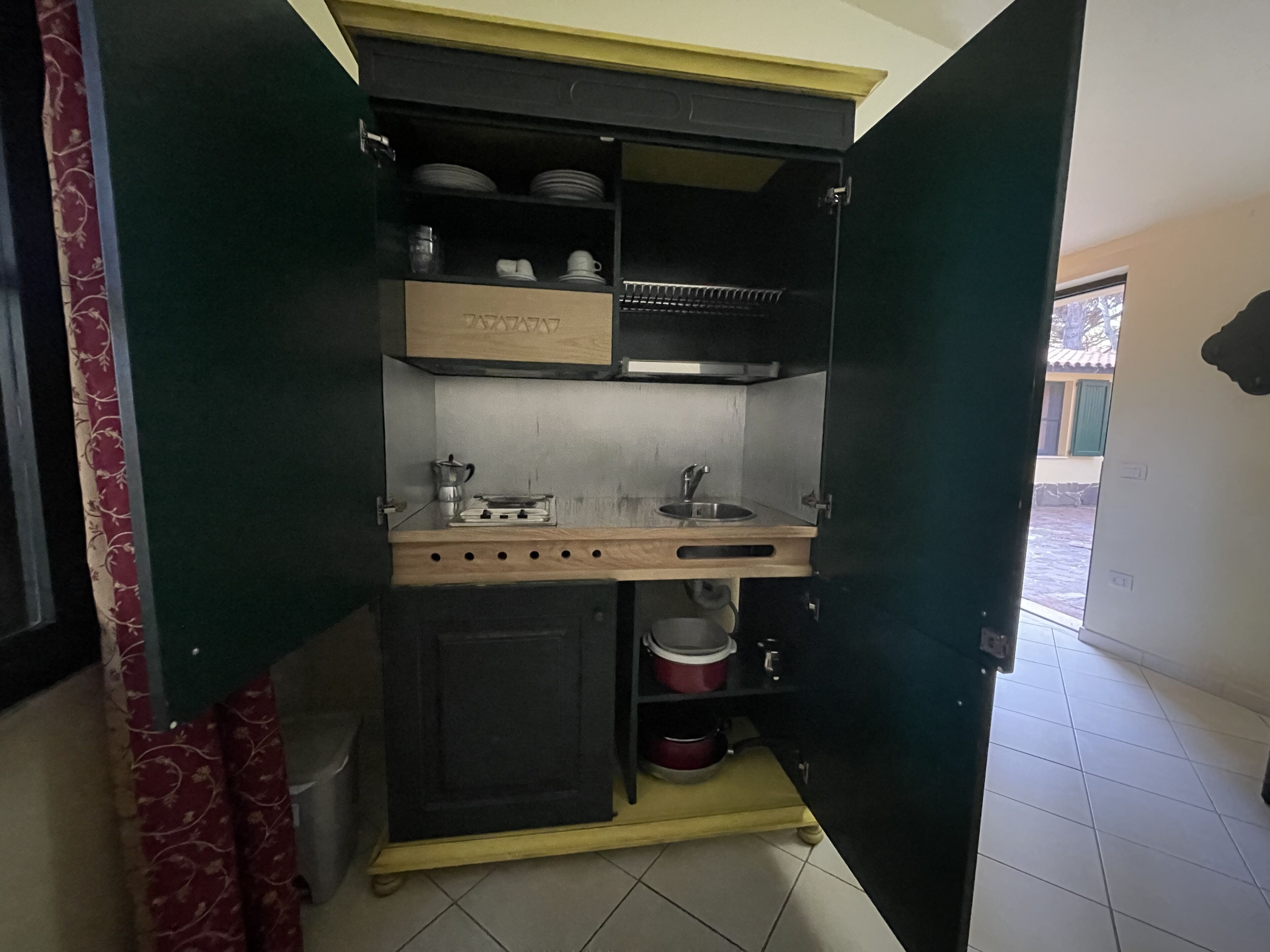 Una cucina compatta con piano cottura integrato, lavello e pensili.