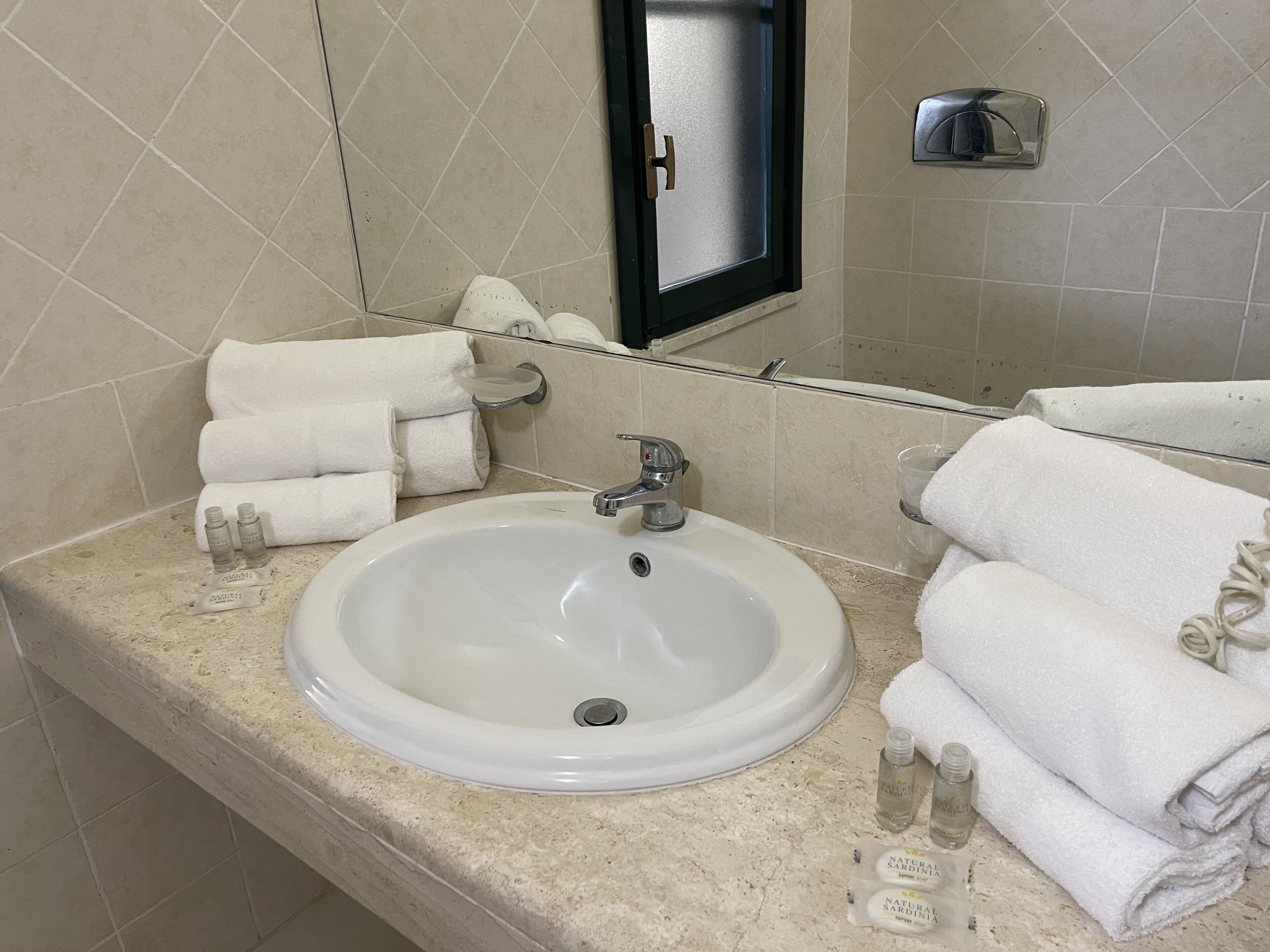 Un baño con un lavabo blanco, varias toallas y artículos de aseo.