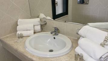 Un baño con un lavabo blanco, varias toallas y artículos de aseo.