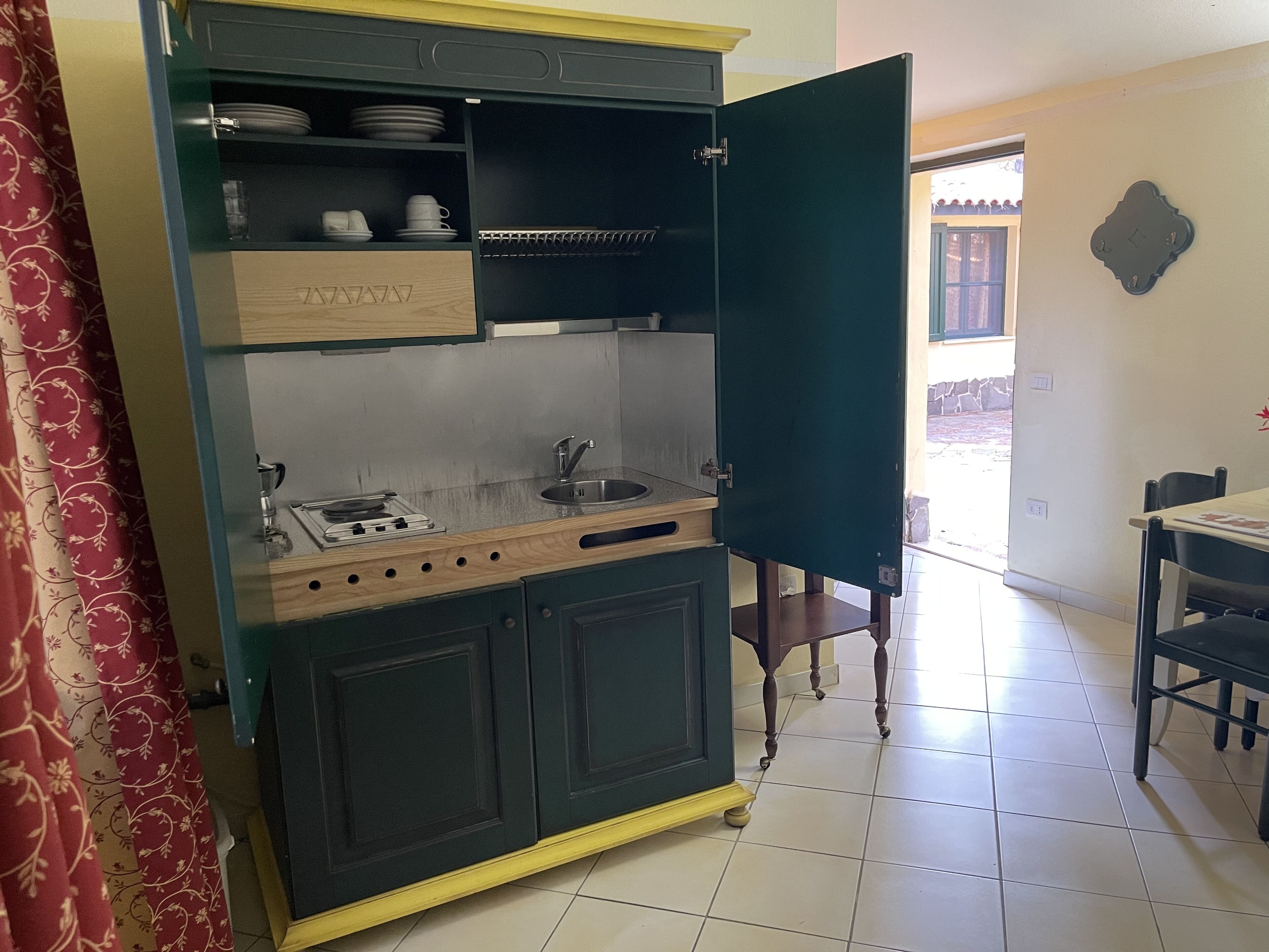 A kitchen with a stove, sink, and open cabinet doors.