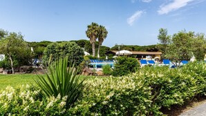 A resort with a pool area, palm trees, and lush greenery. - Ala Birdi Residence  (Arborea)