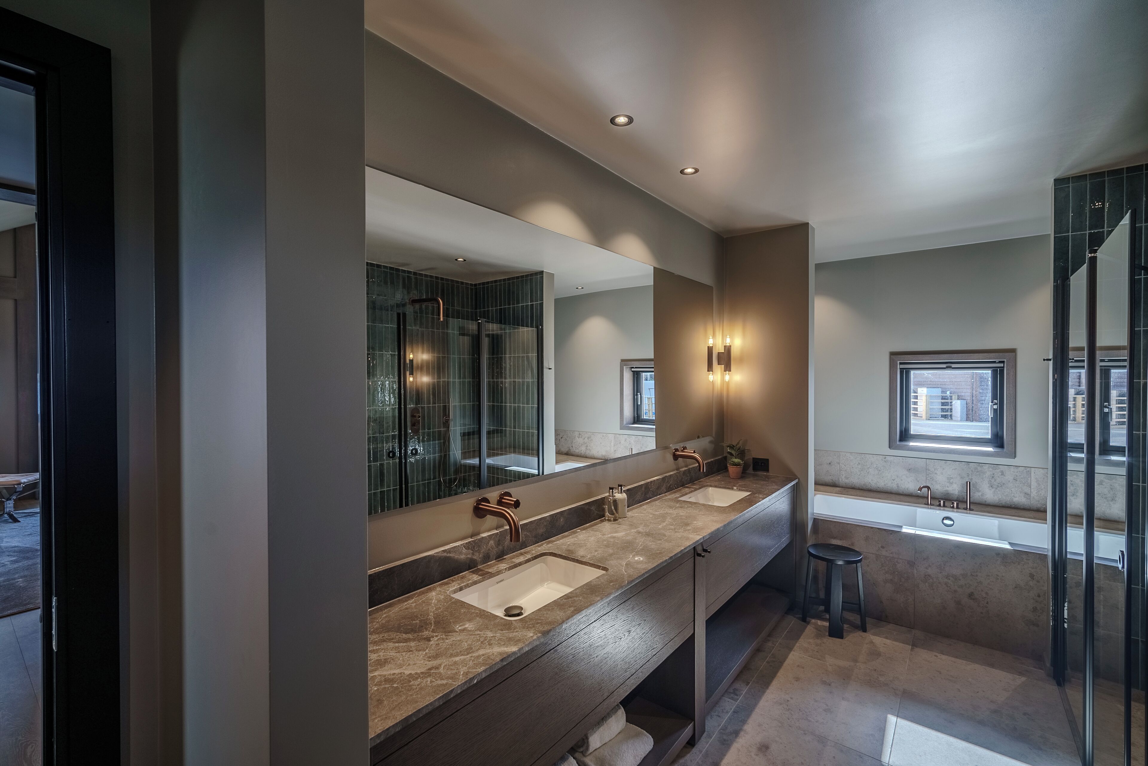 A modern bathroom with two sinks, a large mirror, and a glass shower enclosure.