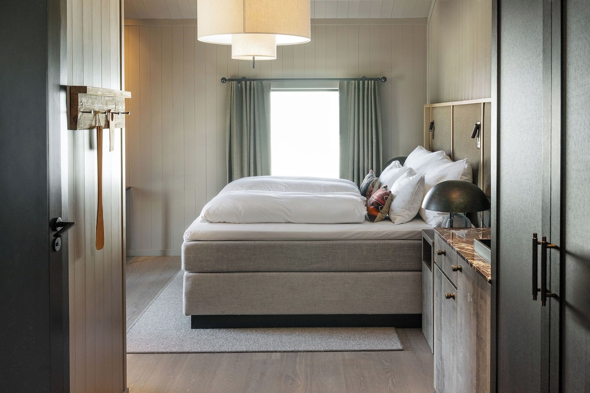 A bedroom with a bed, bedside tables, a lamp, and a wardrobe.