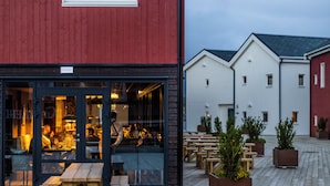 A restaurant with outdoor seating, wooden tables, and potted plants. - Henningsvær Bryggehotell - by Classic Norway Hotels (Vagan)