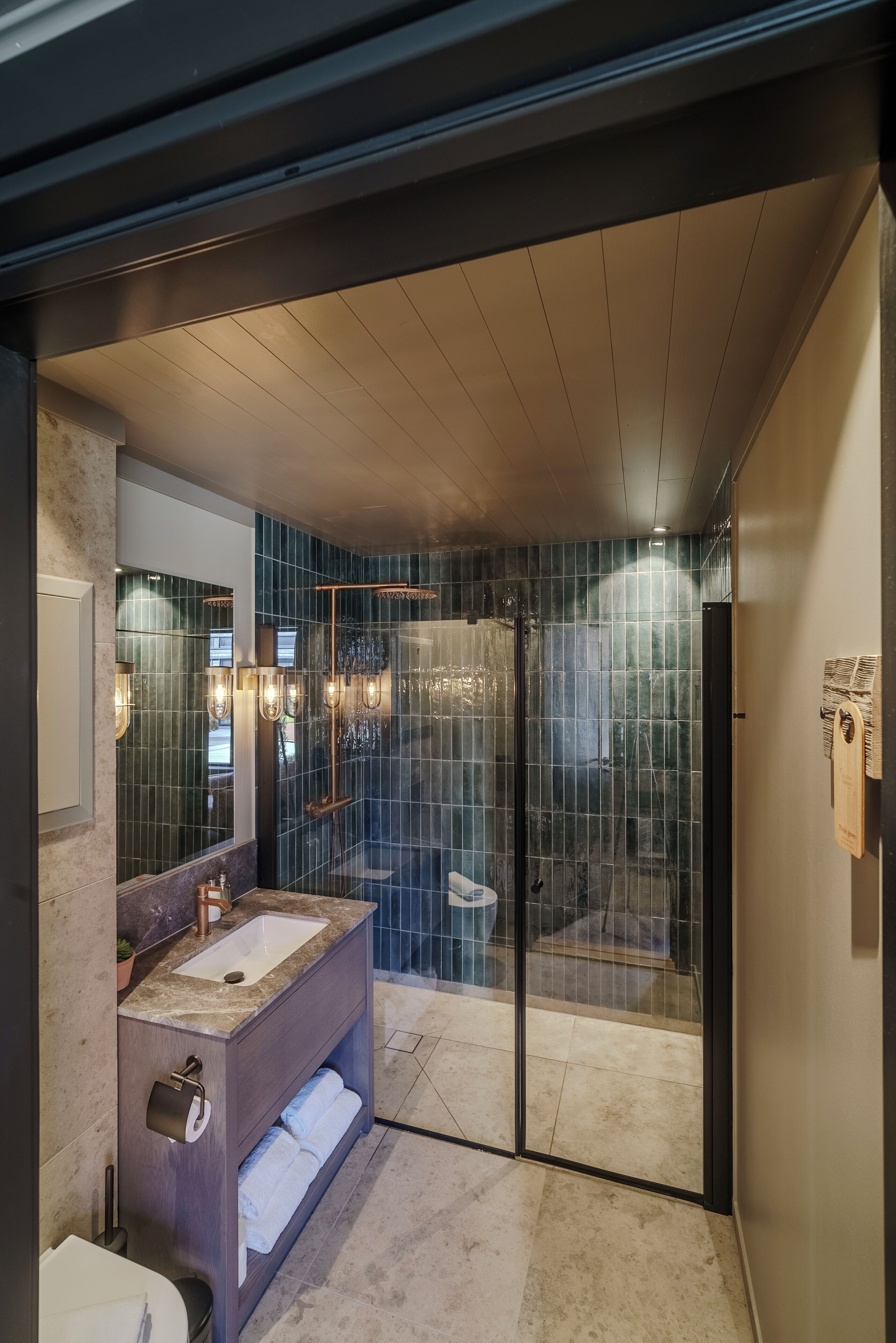 A modern bathroom with a glass-enclosed shower, a marble sink, and a towel rack.