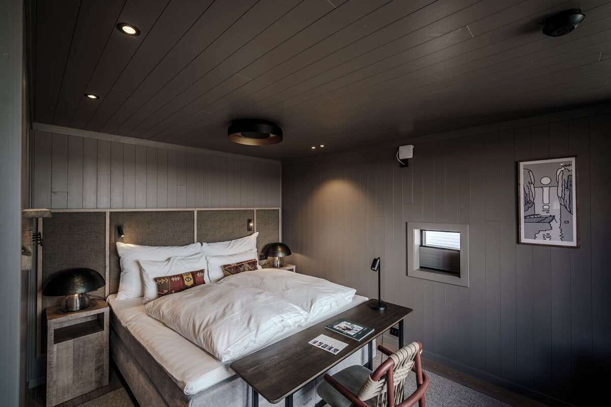 Une chambre à coucher moderne avec un lit, des tables de chevet, un bureau et une chaise.