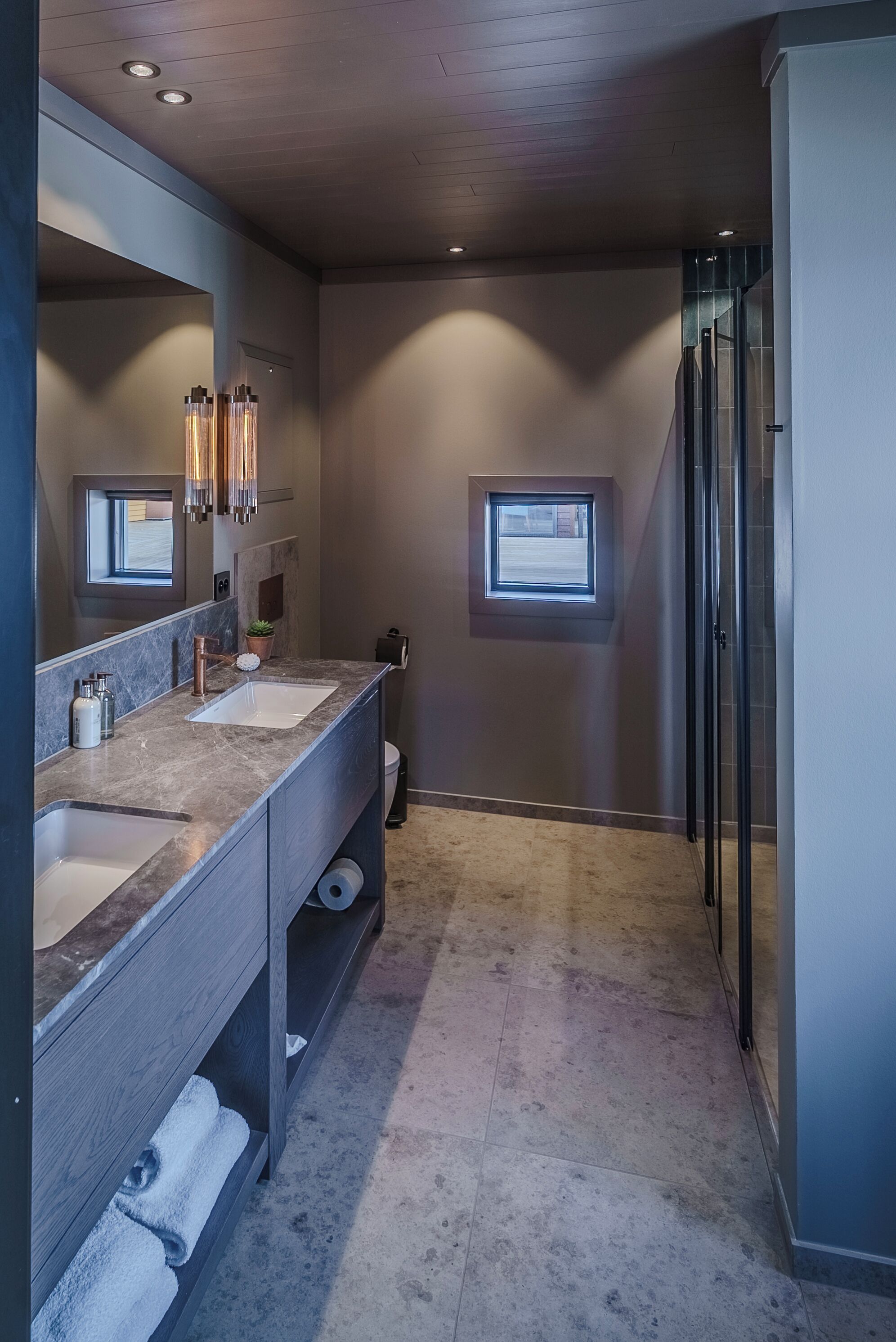 Un baño moderno con dos lavamanos, un espejo grande y una ducha a ras de suelo.