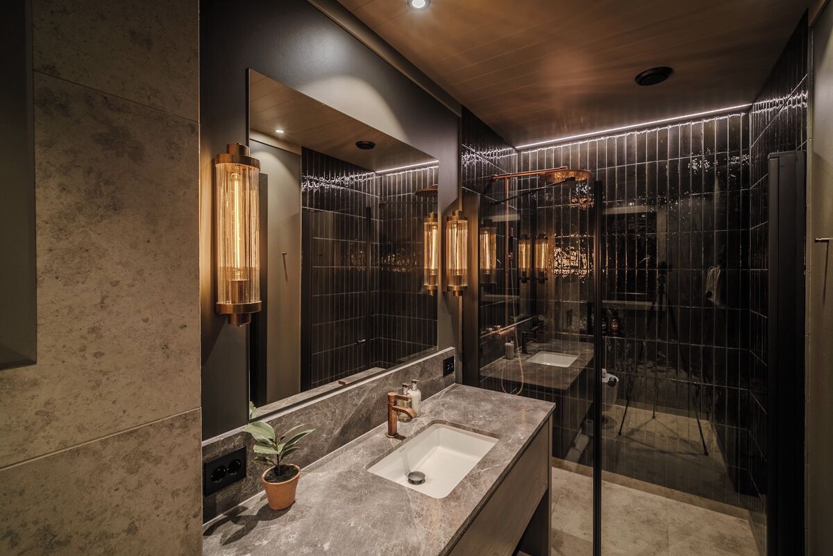 Un baño moderno con un espejo grande, dos lavamanos y un box de ducha de vidrio.