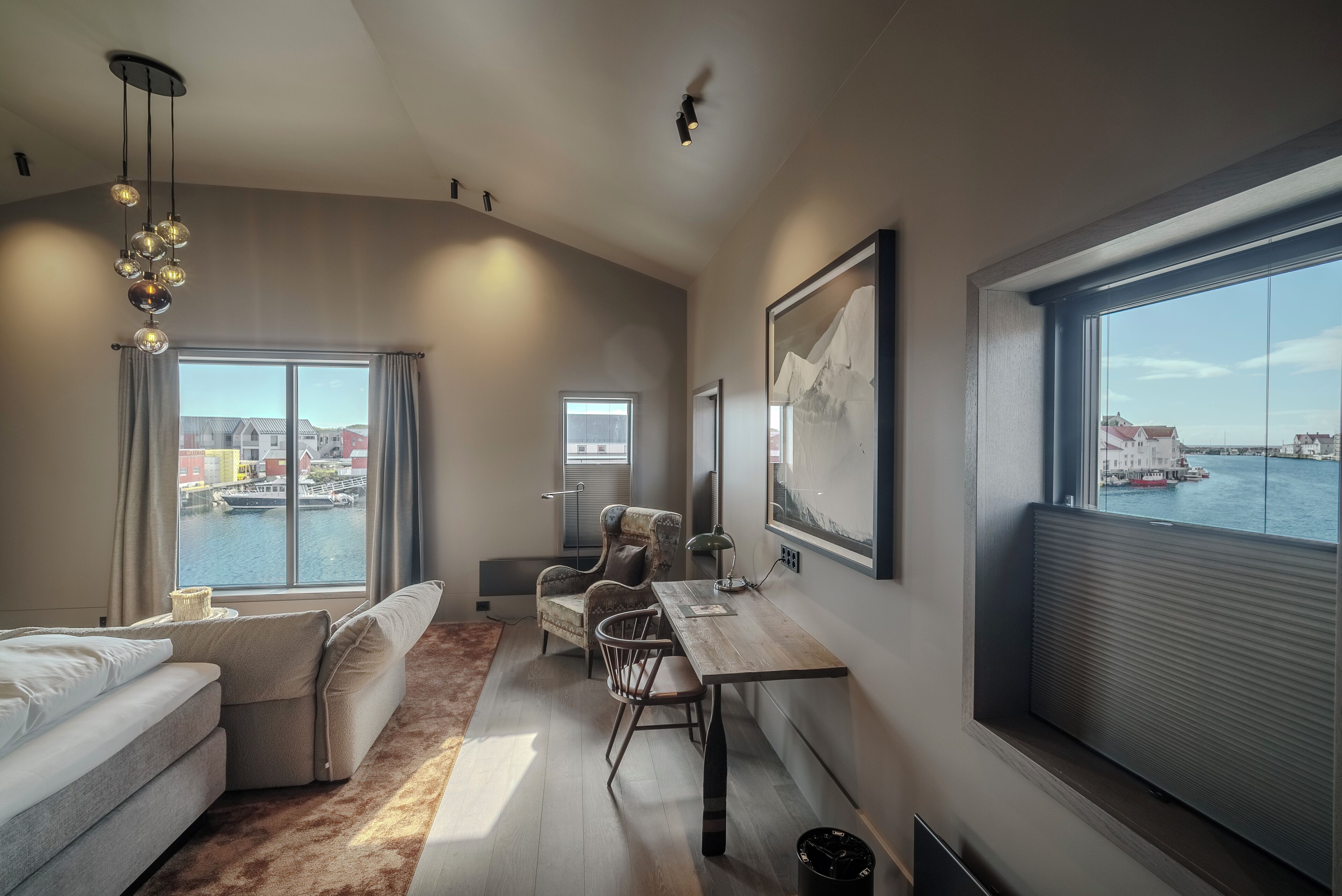 A modern room with a large window, a sofa, a table, and a chair.