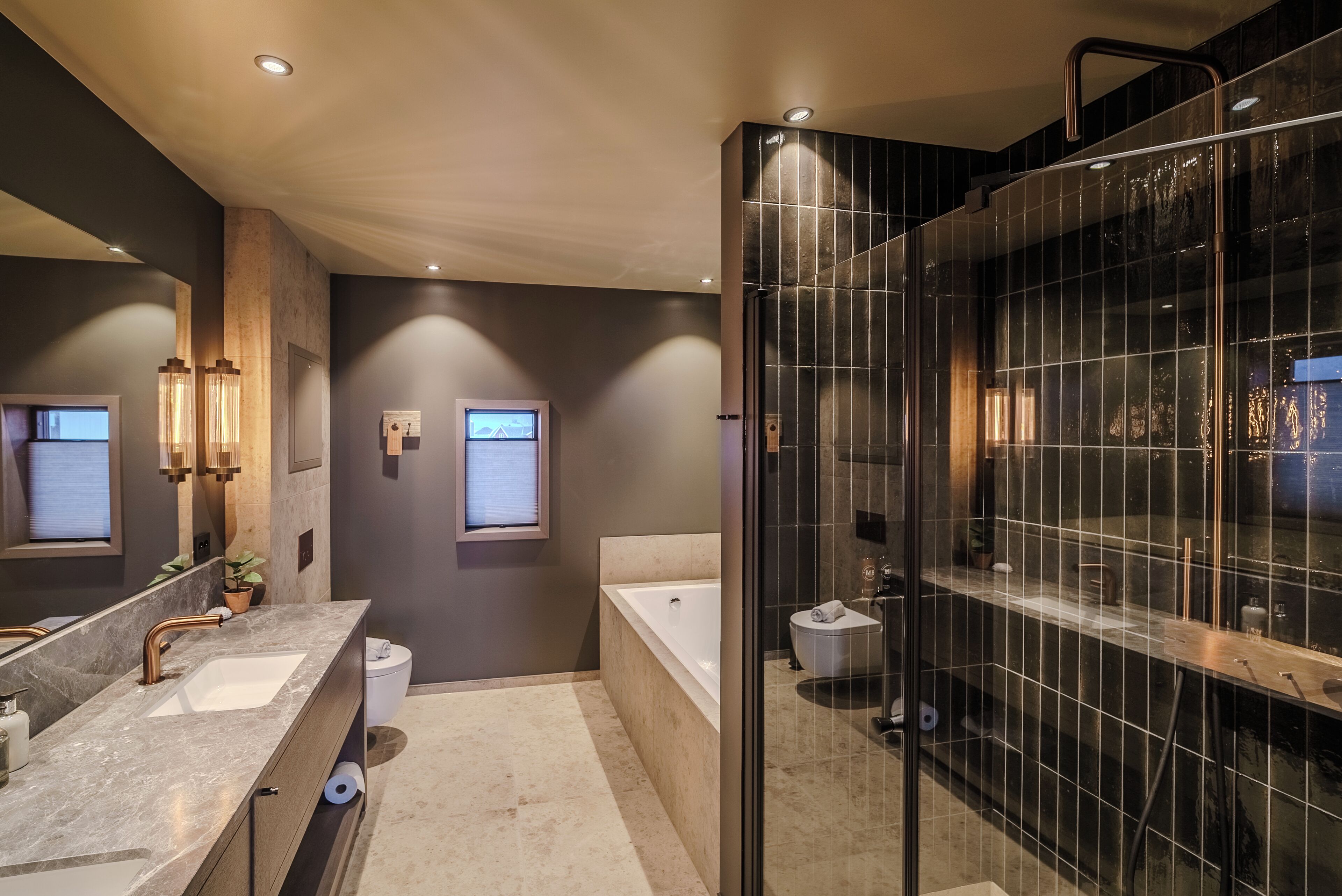 Un baño moderno con un espejo grande, lavamanos dobles, una bañera y una zona de ducha con mampara de cristal.