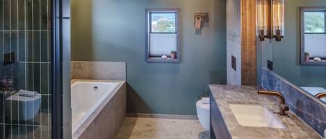Un baño moderno con una bañera grande, dos lavabos y una ducha a ras de suelo.