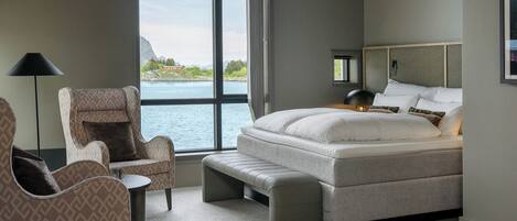 A bedroom with a large window, a bed, a chair, and a small table.
