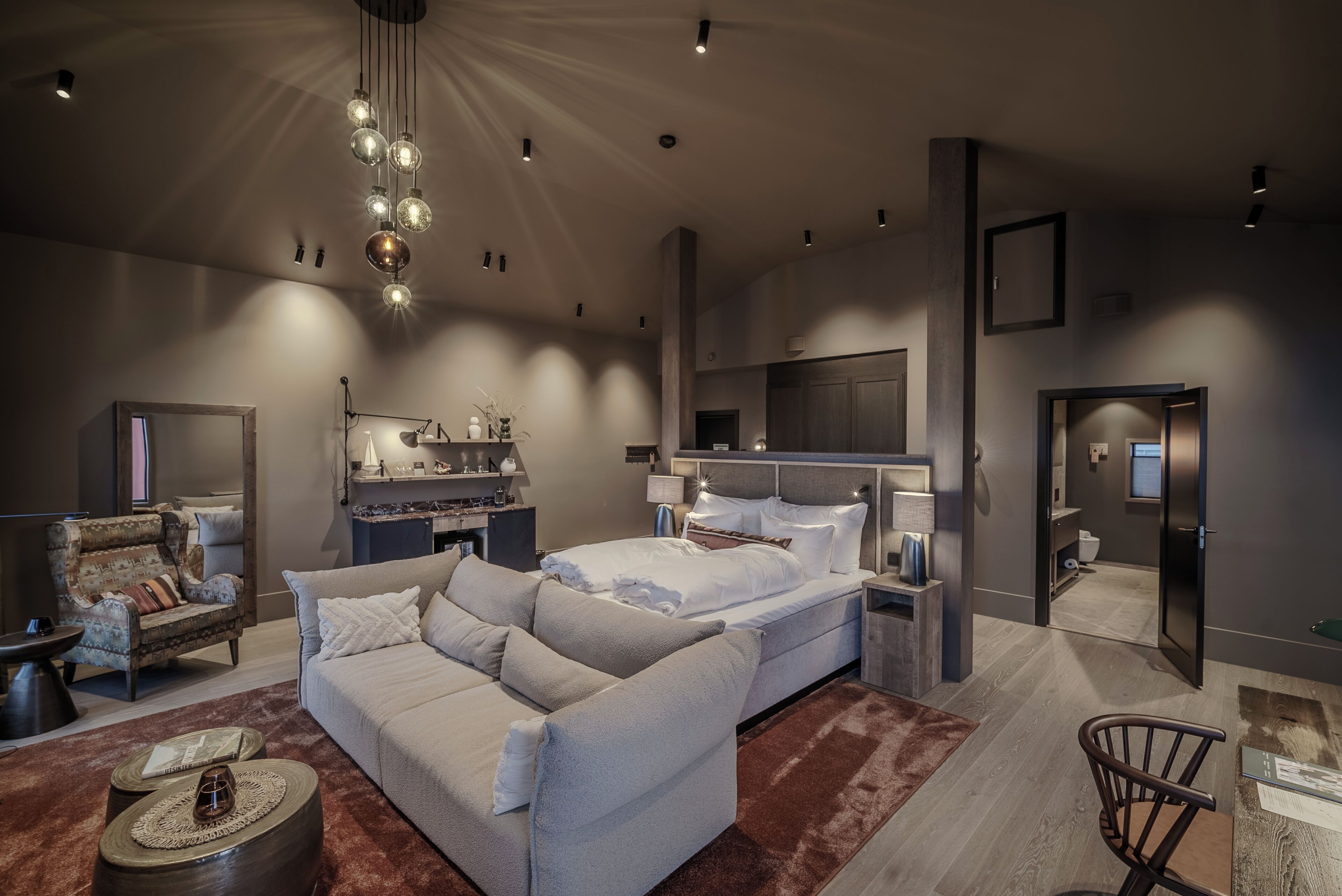 Un dormitorio moderno con una cama grande, un sofá, un escritorio y una silla.
