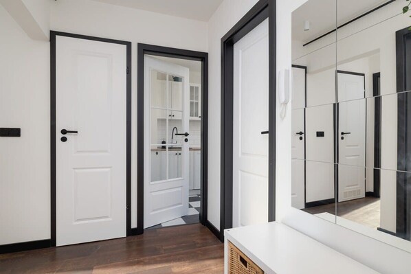 A hallway with white doors and a mirrored wall reflecting the room.