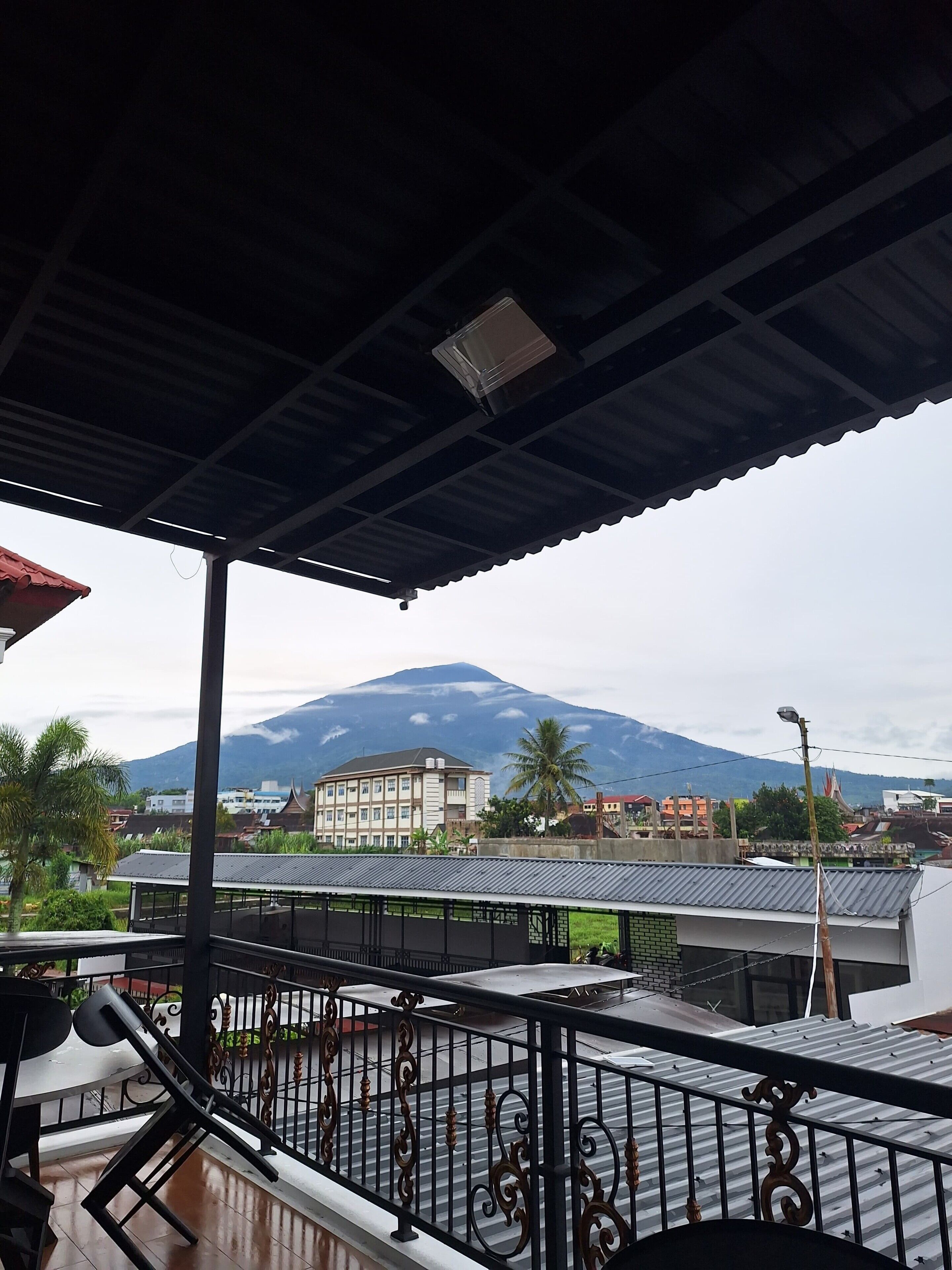 A balcony with a view of a mountain and buildings in the background.