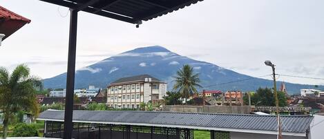 Un balcón con vista a una montaña y edificios al fondo.