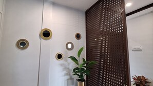Un intérieur moderne agrémenté d’une cloison en bois, d’une plante en pot et de miroirs décoratifs sur le mur.