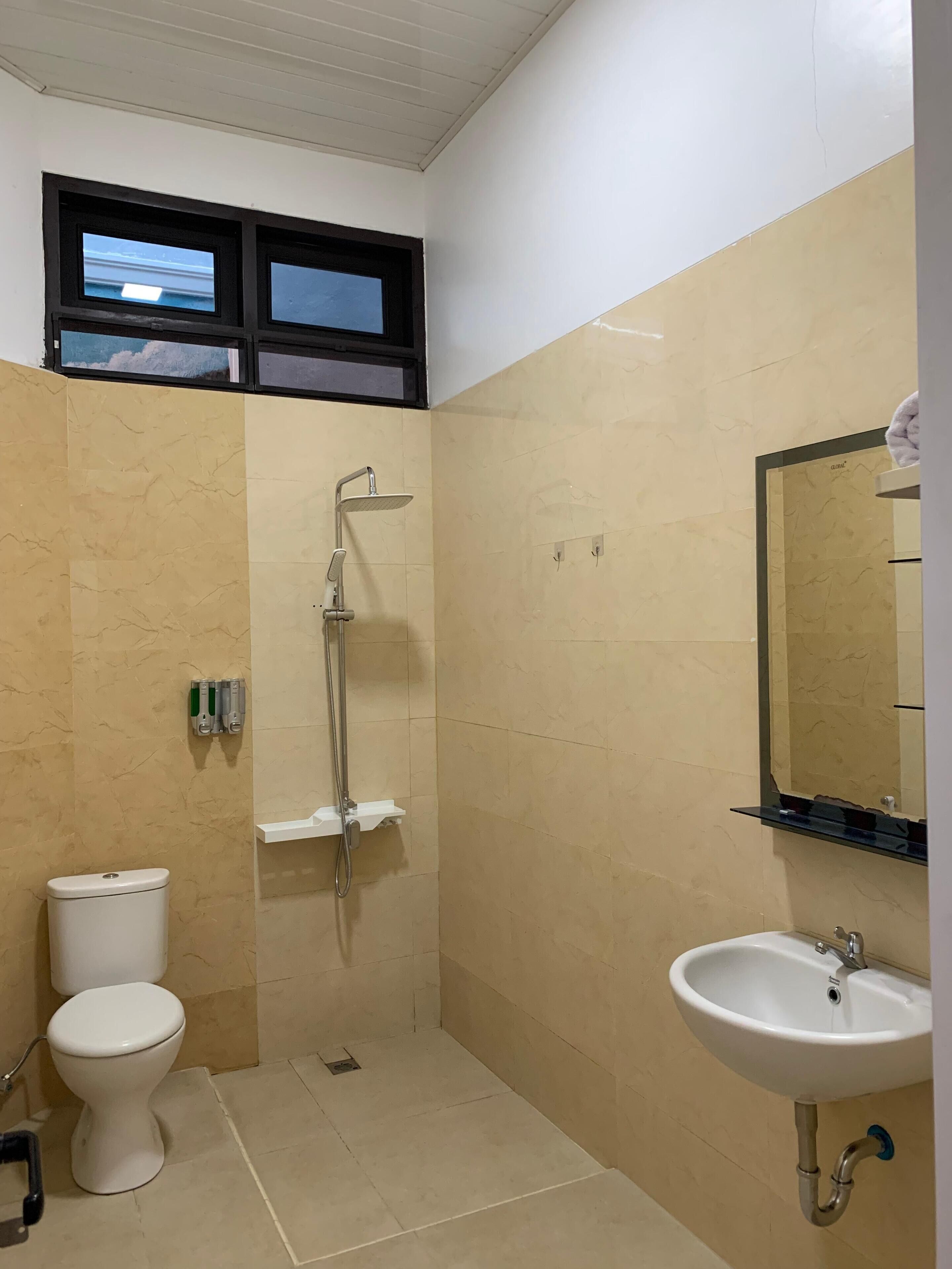 Een kleine badkamer met toilet, douche en wastafel.