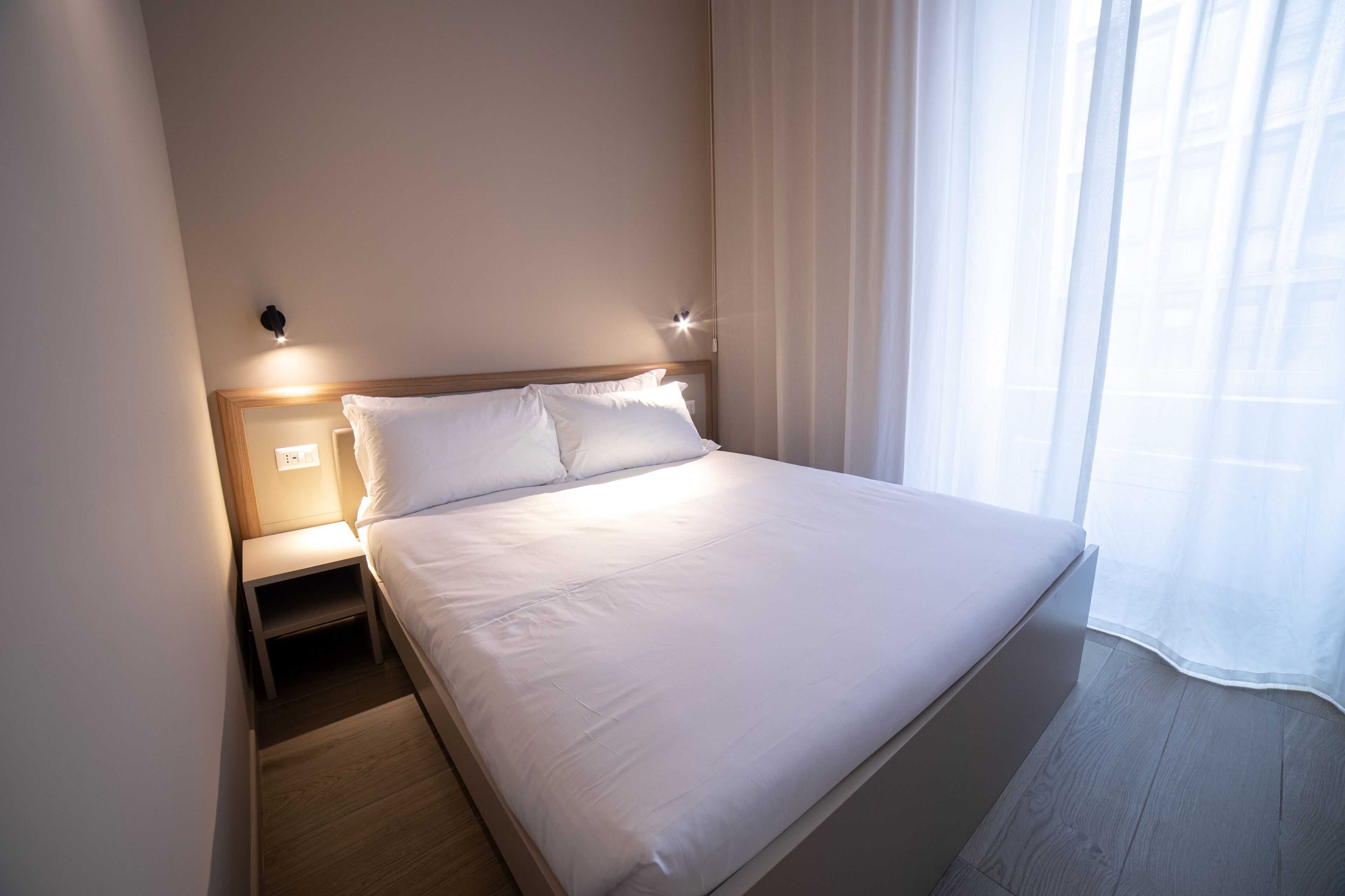 En pænt redt seng med hvide sengetøj i et hotelværelse.