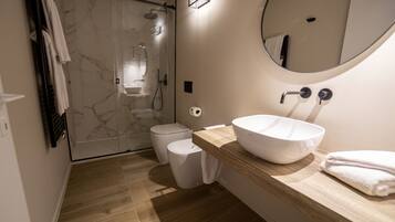 A modern bathroom with a large mirror, a wooden vanity, a white sink, a toilet, and a shower enclosure.